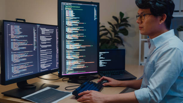 les jeunes développeurs de logiciels asiatiques utilisant un ordinateur pour écrire du code assis au bureau avec plusieurs écrans travaillent au bureau la nuit. développement de programmeurs. - python language photos et images de collection