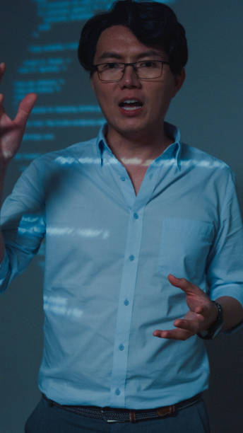 istock Closeup young Asian man software developers mentor leader manager talking to executive team analyzing source code in office at night. Programmer development. Vertical Screen. 1646501682