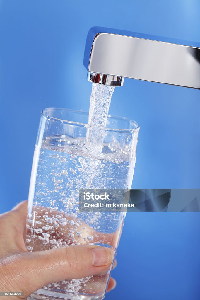 Llenar un vaso de agua. Fondo azul. - Foto de stock de Agua del grifo libre de derechos