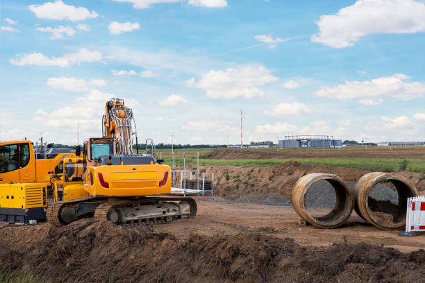 istock Many heavy industrial machines big large concrete sewage pipes stack warehouse construction site near Leipzig Halle airport against blue sky background. Highway road construction excavator earthworks 1646511291