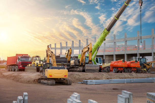 muitos equipamentos de máquinas industriais pesadas coloridas e multiclorados diferentes na área de estacionamento do canteiro de obras contra o desenvolvimento da infraestrutura da cidade de construção de armazéns. venda de locação de veículos com - construction - fotografias e filmes do acervo