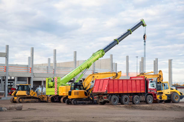 istock Many different multiclored colorful heavy industrial machinery equipment at construction site parking area against warehouse building city infrastructure development. Commercial vehicles rental sale 1646522134