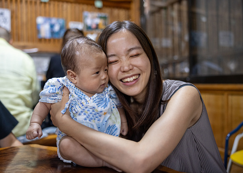 Mother embracing her baby in Japanese restaurant