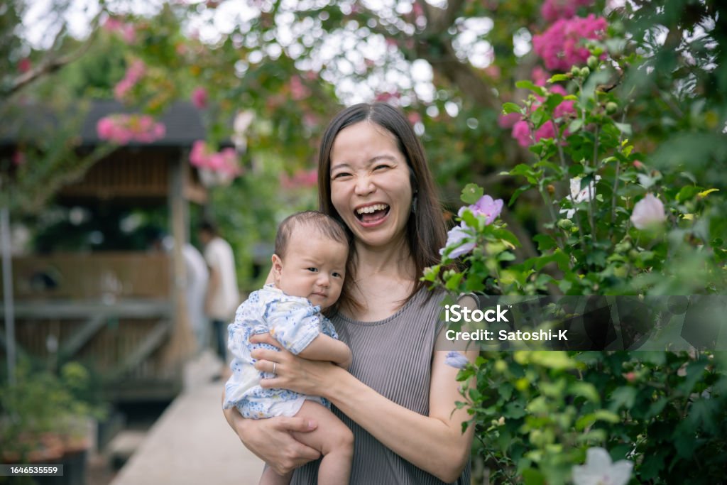 Happy portrait of mother and her baby standing nearby hibiscus flower Japanese Ethnicity Stock Photo