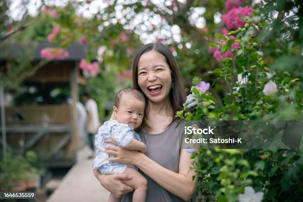 Happy Portrait Of Mother And Her Baby Standing Nearby Hibiscus Flower Stock Photo - Download Image Now