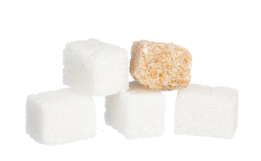 White sugar cubes and a teaspoon on blue background