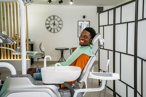 Young cheerful black man in a dentist's office, ready for an examination