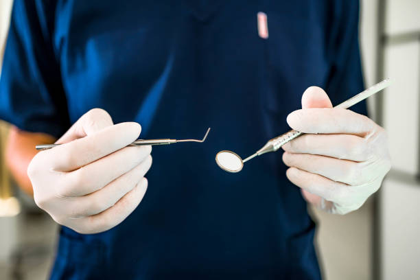 Dentist with white gloves holding a set of metal dental equipment tools for dental care