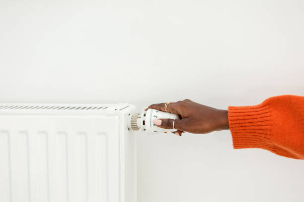 istock Woman adjusting temperature on heating radiator 1646545165