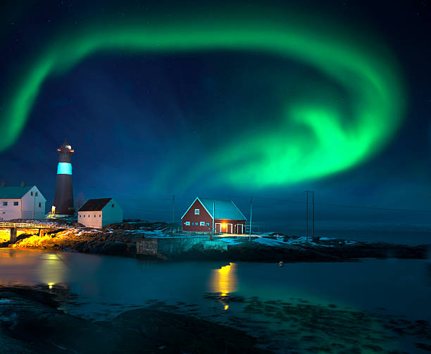 Spectacular shape of northern lights (Aurora borealis) over lighthouse seaside in winter. 