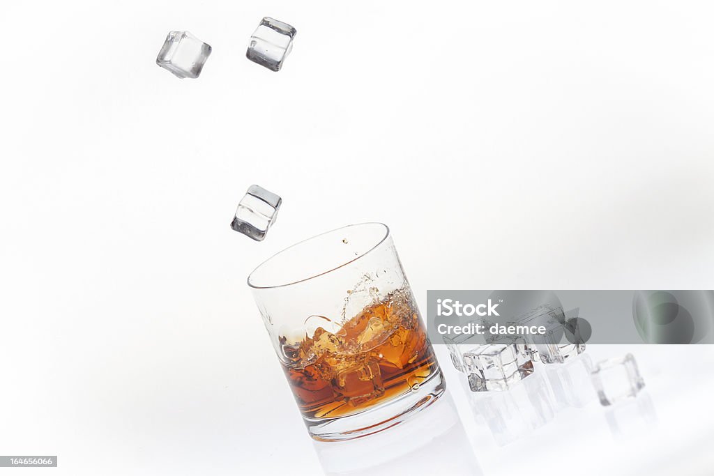 Whisky sulle rocce schizzati da cubi cubetti di ghiaccio - Foto stock royalty-free di Versare