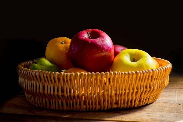 A basket with apples, tangerines, and pears.