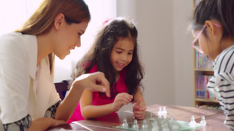 Little girl playing chess with friend in the classroom.