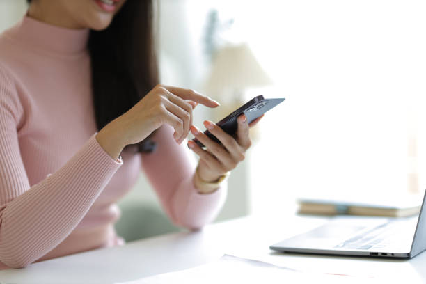 istock Attractive young Asian woman using smartphone in office at home. 1646568318