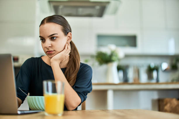 istock A woman uses a laptop in the kitchen while having breakfast in the morning. 1646573728