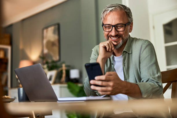 istock A cheerful bearded male freelancer using a mobile phone and laptop at the home office. 1646574924