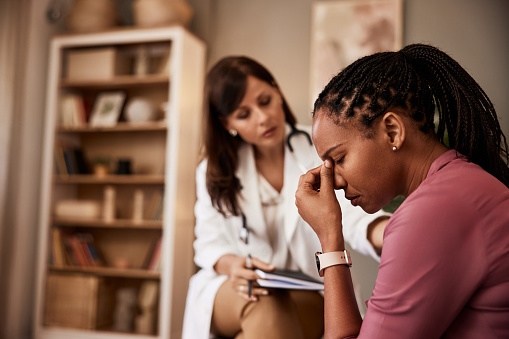 An African-American female patient having a hard period in life and talking with a female psychologist.