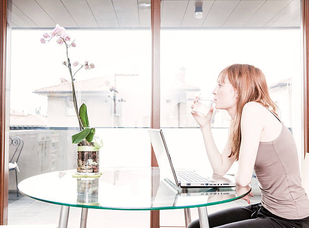 Drinking Water. Woman at Home With Laptop stock photo