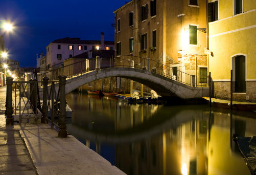 Picture shows a small canal in venice at night.