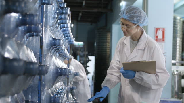 Woman worker checking plastic bottle in water factory