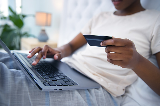 Laptop, hands and credit card by woman in a bed for online shopping, survey or sign up membership in her home. Keyboard, search and female customer with ecommerce, sale or payment in a bedroom
