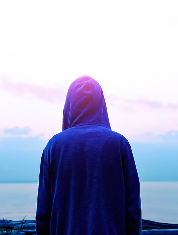 Rear View Silhouette of the Man in a Hoodie on the Sea Background
