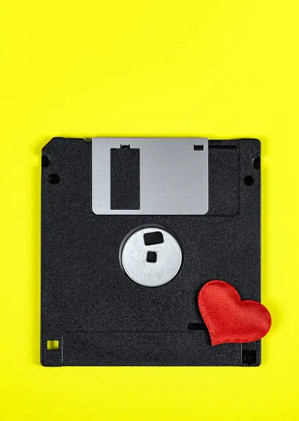 Floppy Disk Drive with a Red Heart on the Yellow Paper Background closeup