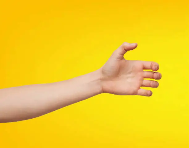Close-up of an Asian man's hand in a grab pose, isolated on a yellow background.