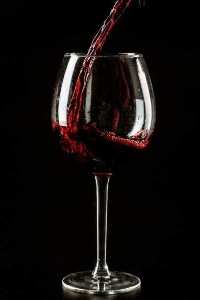 istock Red wine being poured in a wine glass on a dark background 1646621159