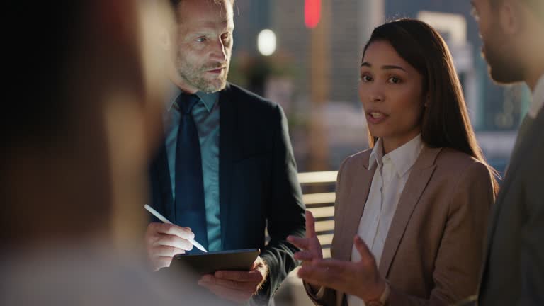 Night, meeting and business people in conversation in the city on rooftop planning project together. Discussion, diversity and group of lawyers working overtime on legal case in collaboration in town