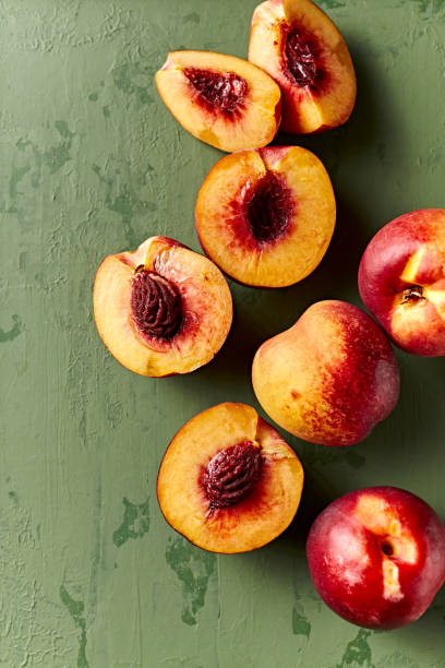 Whole and halved nectarines on rustic painted background. Top view. Copy space stock photo