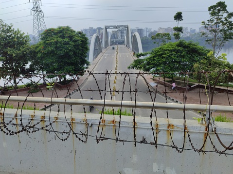 A beautiful view of barbed wire fences, trees, bridges, electric towers and the sky.