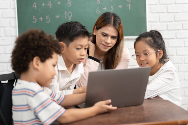istock Teacher woman teaching children with computer notebook in class room 1646693404