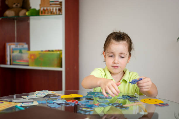istock Cute little girl solving puzzles at home 1646701199