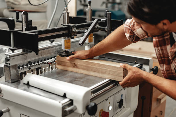istock Young carpenter operating machine for wood processing at a furniture factory 1646708608