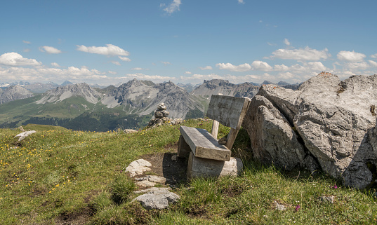 Wonderful view from the Weisshorn mountain in Arosa, Switerland on the surrounding alpine mountains and valley. A resting bank,bench is standing in the foreground.