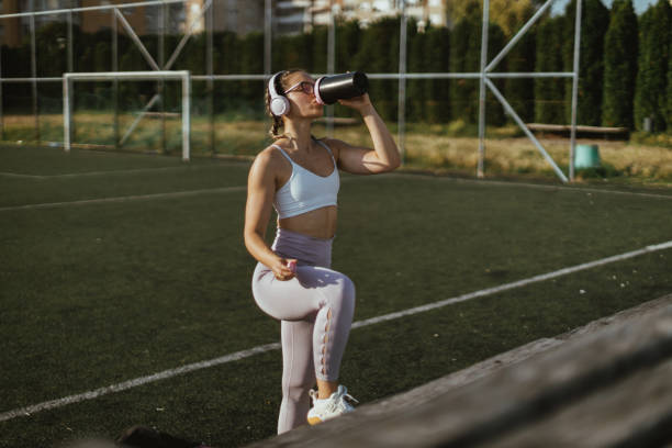 istock Woman using wireless headphones and drinking water on the running track 1646710995