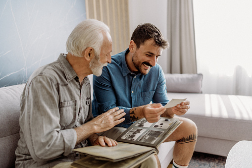 Senior man showing photographs to his son