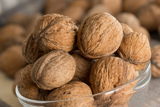 Whole walnuts stacked in glass bowl stock photo