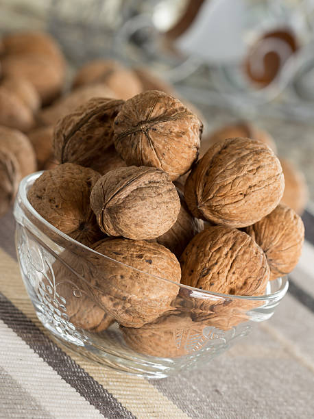 Walnuts in glass bowl placed on fabric stock photo