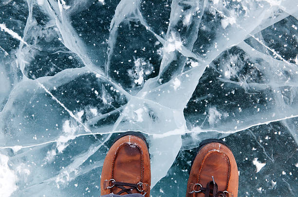 istock Cracked black ice under a pair of brown shoes 164674120