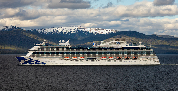 ALASKA, USA - June 13, 2023 - Princess Cruises ship Discovery Princess cruises the waters near Ketchikan, Alaska with snow-capped mountains in the background