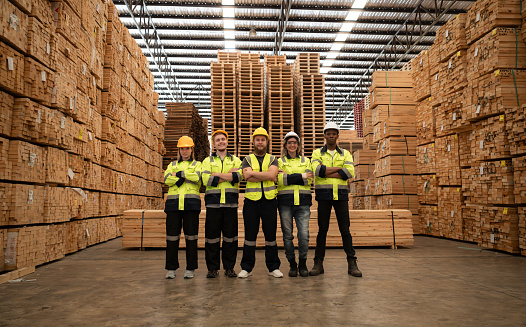 Portrait of a group of workers work in a woodworking factory, Standing with arms crossed in a wooden warehouse.