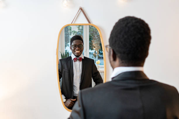 istock Black men in suit observing himself in the mirror, while preparing for a house party 1646773864