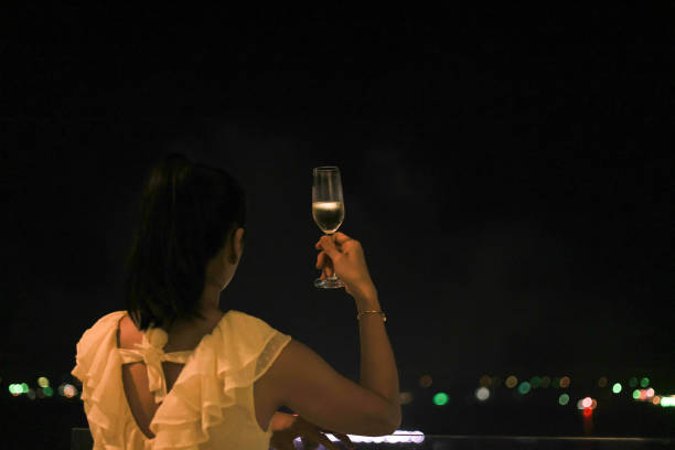 frau in der neujahrsnacht hält ein beschlagenes kaltes glas champagnerwein vor einem schönen feuerwerkshintergrund in der hand - sparkler sparks new years eve human hand stock-fotos und bilder