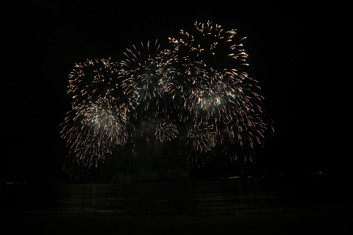 Summer festival or celebration, vibrant colors exploding fireworks against night sky.