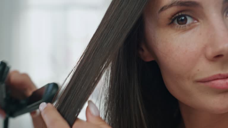 Portrait girl straightening hair home. Lady ironing chevelure enjoying styling