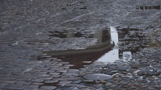 Puddle on old cobblestones road, Raining in European City scene, Tilt Shot