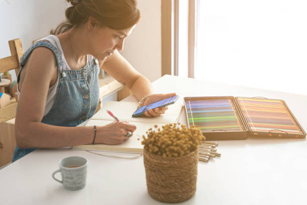 istock Illustrator using her mobile phone for inspiration and to take some references to carry out her work. 1646814334
