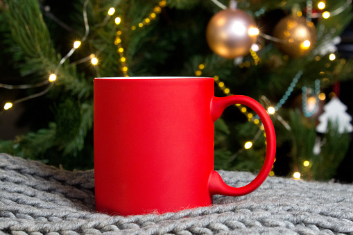 Blank red mug with christmas tree and piano on background,mat tea or coffee cup with christmas and new year decoration,mock up with ceramic mug for hot drinks,empty gift print branding template.